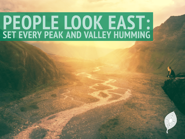 A sun rising over a river valley between two mountains